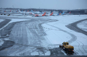 A snow plough waits to help clear snow from around aircraft after overnight snowfall caused the temporary closure of Manchester Airport in Manchester