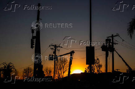 Workers repair a power line damaged by Eaton Fire in Altadena