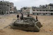 Palestinians look at damaged Israeli military vehicles left behind by Israeli forces in Rafah