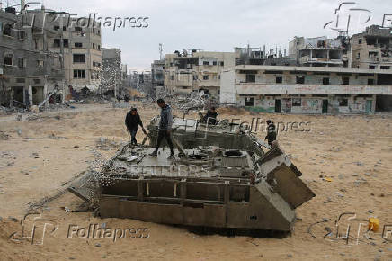 Palestinians look at damaged Israeli military vehicles left behind by Israeli forces in Rafah