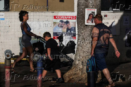 People make their way past images of those taken hostage or killed during the deadly October 7 attack, in Tel Aviv