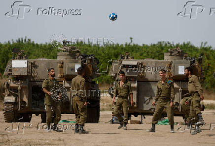 Israeli soldiers play next to military vehicles, near the Israel-Gaza border