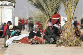 Displaced people who fled from Aleppo countryside, sit together with belongings in Tabqa