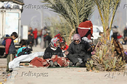 Displaced people who fled from Aleppo countryside, sit together with belongings in Tabqa