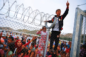 FILE PHOTO: Refugee youths gesture from behind a fence as officals arrive at Nizip refugee camp near Gaziantep