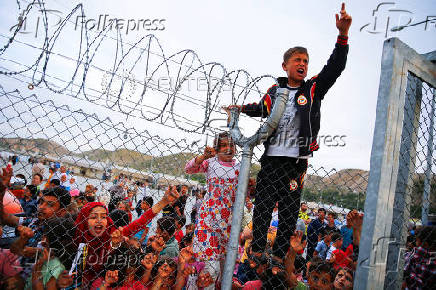 FILE PHOTO: Refugee youths gesture from behind a fence as officals arrive at Nizip refugee camp near Gaziantep