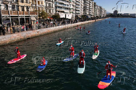 Members of the ThesSUP team wearing Santa Claus costumes paddle off the seafront of Thessaloniki