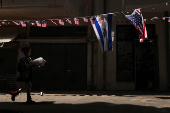 A woman walks past an Israeli and U.S. flags, amid the ongoing conflict in Gaza between Israel and Hamas in the Florentin area of Tel Aviv