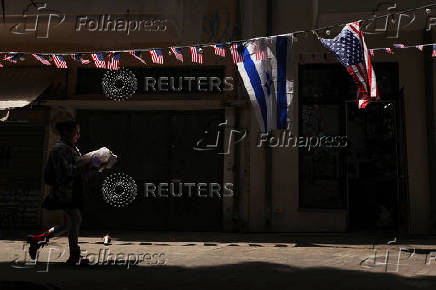 A woman walks past an Israeli and U.S. flags, amid the ongoing conflict in Gaza between Israel and Hamas in the Florentin area of Tel Aviv