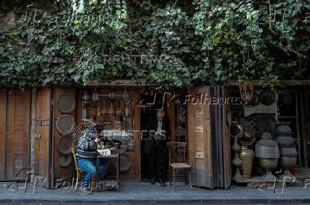 A vendor works on an item at the old city, in Damascus