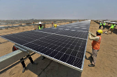 Workers install solar panels at the Khavda Renewable Energy Park of Adani Green Energy Ltd (AGEL)  in Khavda
