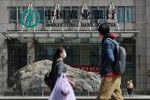 FILE PHOTO: People walk past an office building of Agricultural Bank of China, in Beijing