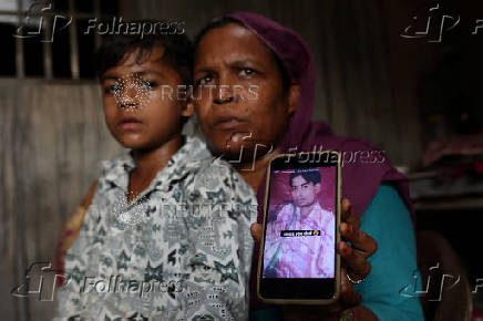 Malika shows her late husband Musharraf's photo on her mobilephone during an interview with Reuters' reporters as her son Rihan,8, sits next to her at their residence in Loni town in the northern state of Uttar Pradesh