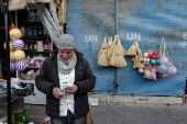 A grocery vendor counts money outside his shop at the old city, in Damascus,