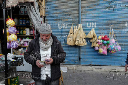 A grocery vendor counts money outside his shop at the old city, in Damascus,