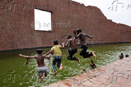 Children jump into the water body of Martyred Intellectuals Memorial at Rayerbazar, to cool themselves during a heatwave in Dhaka