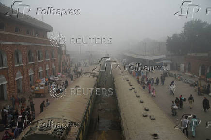 People walk to board trains amid smog and air pollution at a railway station in Lahore