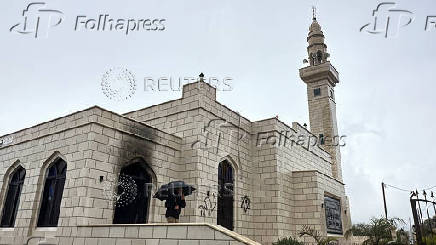 Palestinians check damage to a mosque burned by Israeli settlers in the West Bank