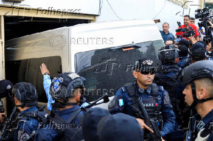 Police officers escort a van allegedly transporting former Honduran Joint Chief of Staff Gen. Romeo Vasquez