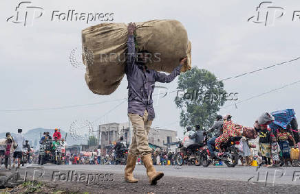 Internally displaced civilians from the camps in Munigi and Kibati, carry their belongings as they flee to Goma