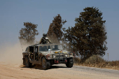 Israeli soldiers ride in a military jeep, near the Israel-Gaza border