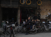 Children sit on a motorcycle with their relative, in Douma