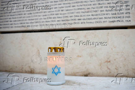 FILE PHOTO: A candle is seen in front of the Wall of Names at the Shoah Memorial in Paris