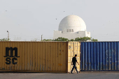 A man walks past shipping containers, used to block the area for security measures, following the visit of the Iranian President Ebrahim Raisi, in Karachi
