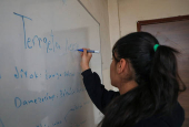 A students writes on a board in a classroom in Qamishli