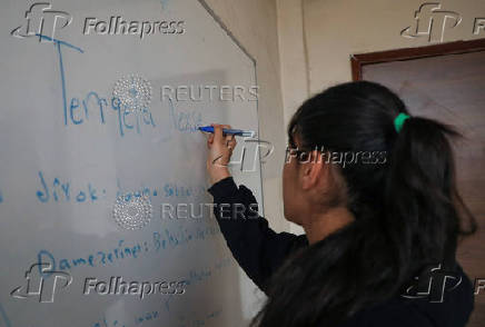 A students writes on a board in a classroom in Qamishli