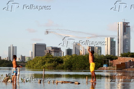 Meninos jogam rede de pesca no rio Capibaribe, em Recife
