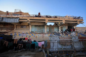A Palestinian man stands atop a building at Palestine Stadium, which was damaged during the Israeli offensive, where displaced people take shelter, in Gaza City