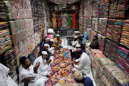 Muslims pray before they eat their Iftar (breaking of fast) meal at a shop during the fasting month of Ramadan in the old quarters of Delhi