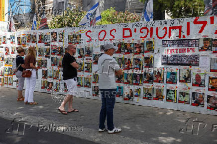 People walk past posters in support of hostages who were kidnapped during the deadly October 7 attack, in Tel Aviv
