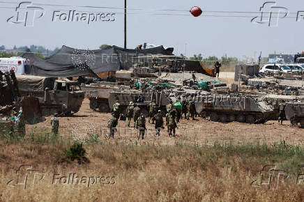 Israeli soldiers walk next to military vehicles near the Israel-Gaza border, amid the ongoing conflict between Israel and the Palestinian Islamist group Hamas, in southern Israel