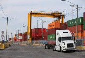 FILE PHOTO: A truck moves past stacked shipping containers at the Port of Montreal