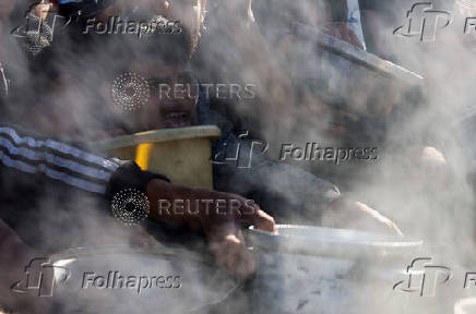 Palestinians gather to receive food cooked by a charity kitchen, amid a hunger crisis, in Khan Younis