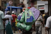 Homem carrega sacolas durante compras na 25 de Maro em SP