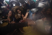 Displaced Palestinians collect donated food in Khan Yunis, southern Gaza