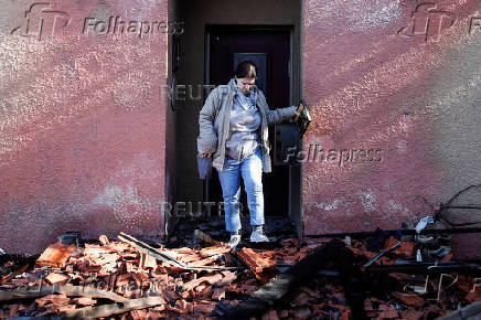 A woman inspects the damage caused by projectiles fired from Lebanon, following the ceasefire between Israel and Iran-backed group Hezbollah, in Metula