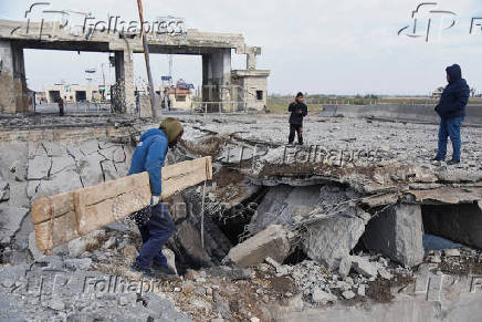 People stand near a damaged site at the Lebanese-Syrian border crossing of Arida