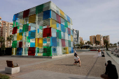 Tourists take photos next to the Cube of the Centre Pompidou Modern Art Museum, in Malaga