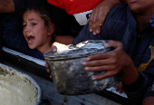 Palestinians gather to receive food cooked by a charity kitchen, amid a hunger crisis, in Khan Younis