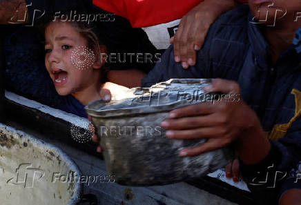 Palestinians gather to receive food cooked by a charity kitchen, amid a hunger crisis, in Khan Younis