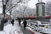 People walk along the sidewalk during the city's first snowfall of the season, on the first day of winter in the Queens borough of New York City