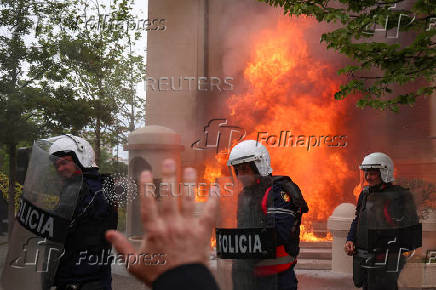 Police officers react as supporters of the opposition hurl Molotov cocktails at the mayor's office, accusing him of corruption, in Tirana