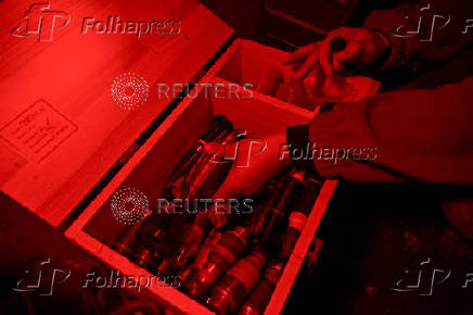 Policeman of the 'Khyzhak' Brigade places custom made miniature drop bombs into a box at a position in a front line near the town of Toretsk