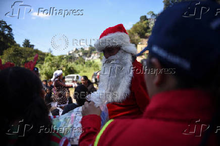 Guatemalan firefighter dressed as Santa Claus rappels down the Vacas Bridge to give toys to children, in Guatemala City