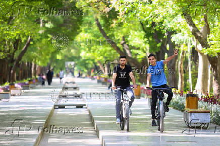 Iranian men ride bicycles, after a reported Israeli attack on Iran, in Isfahan Province