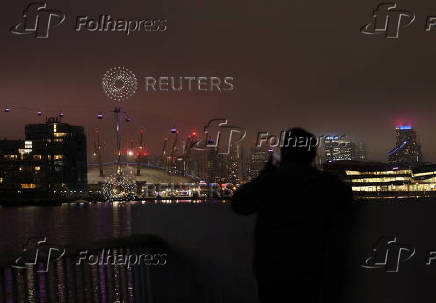 A man watches the Canary Wharf skyline from the Royal Docks during foggy weather in London